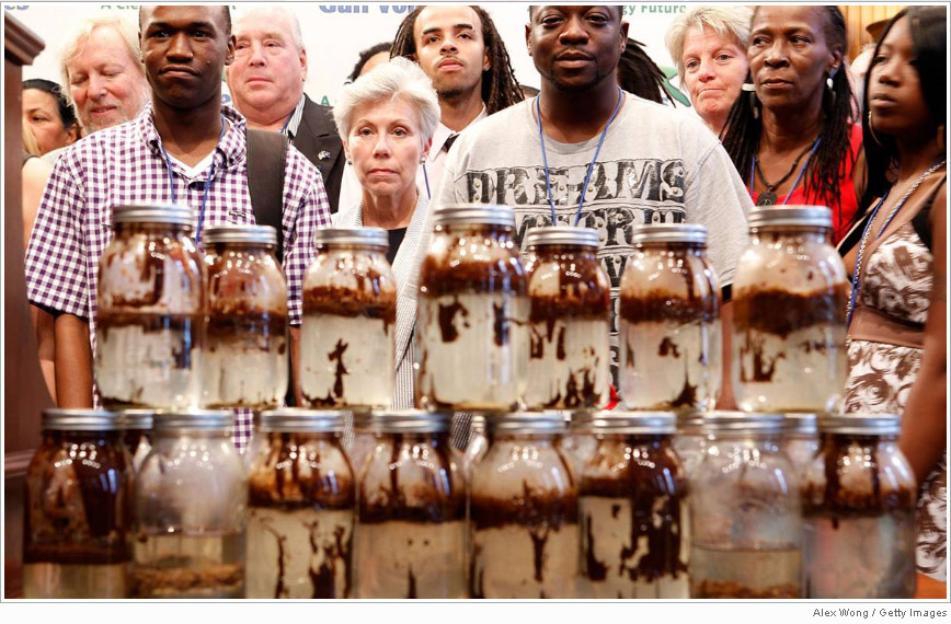 Jars of water mixed with oil collected from the waters of Louisiana and Alabama are stacked in front of Gulf Coast residents as they attend a news conference on Capitol Hill on June 16 in Washington. About 90 residents from the Gulf Coast gathered to tell